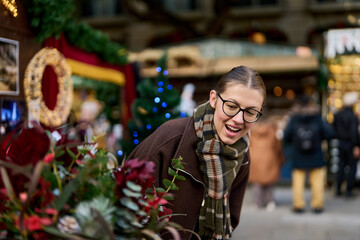 Cheerful young woman looking for New Year decorations in traditional street market