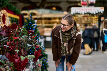 Cheerful young woman looking for New Year decorations in traditional street market