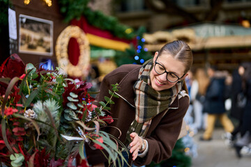 Cheerful young woman looking for New Year decorations in traditional street market
