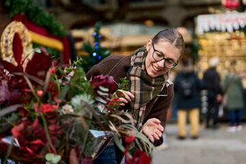 Cheerful young woman looking for New Year decorations in traditional street market