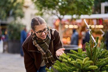 Cheerful young woman looking for New Year decorations in traditional street market