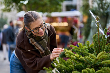 Cheerful young woman looking for New Year decorations in traditional street market