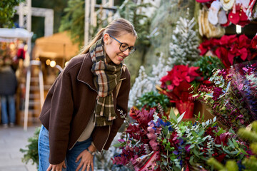 Cheerful young woman looking for New Year decorations in traditional street market