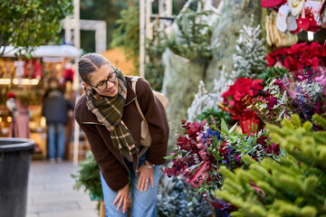 Cheerful young woman looking for New Year decorations in traditional street market