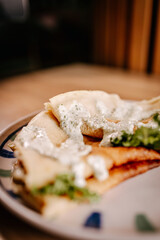 Soft focus close-up of savory crepes filled with minced meat and topped with creamy herb sauce. Cozy homemade comfort food in warm light