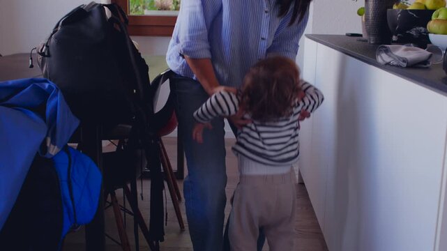 Toddler reaching up to mother asking to be held creating warm moment of attachment affection and early dependence inside cozy home environment with soft interaction and gentle connection