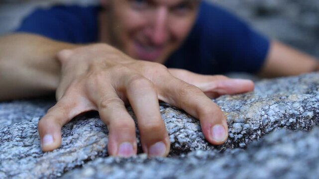 Close up view of a climber's hands desperately searching for a grip on a rocky ledge, symbolizing determination, challenge, and the will to succeed against all odds in an outdoor sport