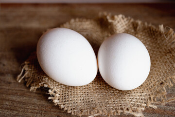 Side view of two white eggs resting on a piece o frustic fabric.Organic food concept. copy space