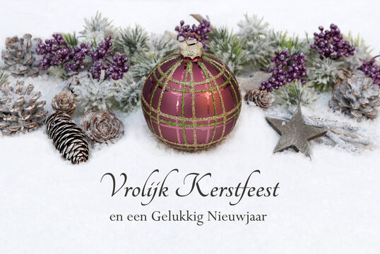 Kerstkaart: Nederlandse kerstgroeten tegen een winterse achtergrond, met kerstversieringen, kerstballen en dennentakken in de sneeuw. Fijne kerst en een gelukkig nieuwjaar!