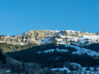 roche parstire dans le beaufortain, une falaise abrupte enneig&eacute;e avec des sapins et des chalets d'alpage