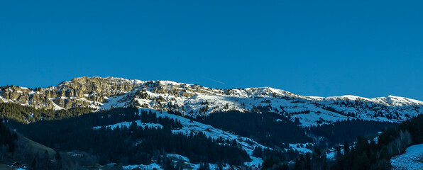 roche parstire dans le beaufortain, une falaise abrupte enneig&eacute;e avec des sapins et des chalets d'alpage