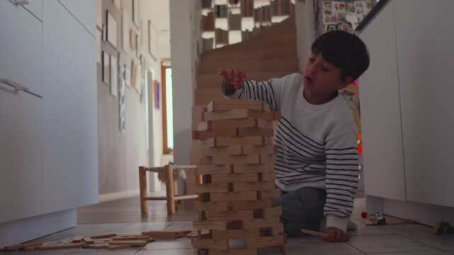Boy building rounded wooden tower in hallway corner with focused patience while arranging blocks carefully during calm creative playtime showing steady concentration and balanced construction