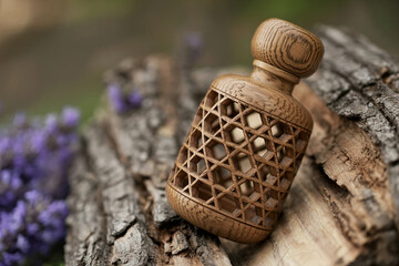 Ornate wooden bottle on rustic tree bark with purple flowers