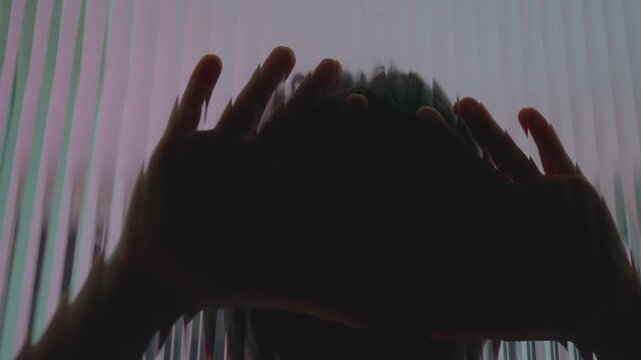 Child silhouette leaning against textured glass with arms raised overhead, themes of emotional overwhelm isolation depression trauma and childhood mental health struggles