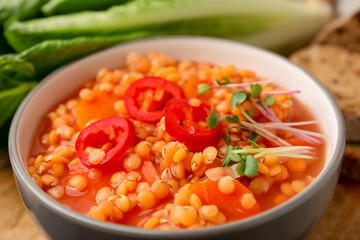 Delicious lentil soup with vegetables served on table, closeup