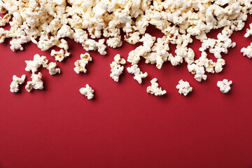 Fresh tasty popcorn on red background, flat lay. Space for text