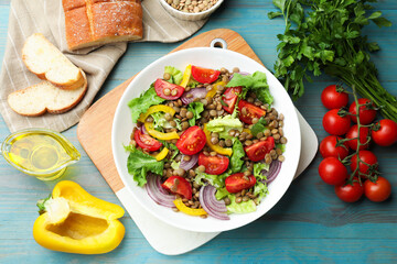 Delicious lentil salad and ingredients on light blue wooden table, flat lay
