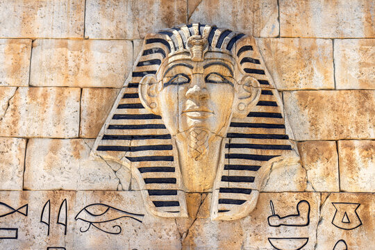 Stone pharaoh tutankhamen mask on sandy background