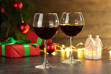 Glasses of red wine and Christmas decor on grey table