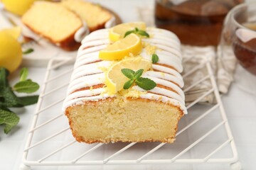 Delicious lemon cake with glaze, fresh fruit slices and mint on light table, closeup