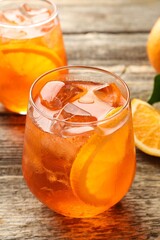 Glasses of refreshing spritzer cocktail and oranges on wooden table, closeup