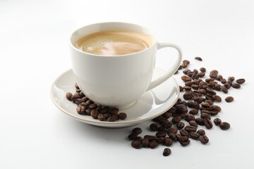Cup of aromatic coffee and roasted beans on white background, closeup
