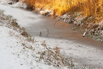 Frozen solid, stream in countryside frozen solid on a winters day preventing birds and animals from swimming or drinking in it.