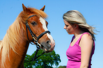 Pretty blond girl and her chestnut pony horse share a moment of love and trust outdoors on a summers day in rural Shropshire UK 