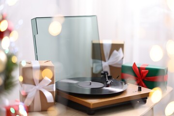 Turntable with vinyl record and gift boxes on wooden table. Christmas music