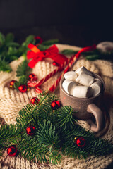 Cup of hot chocolate with marshmallow in knitted wool christmas setting. Hot winter drinks in christmas environment. Cozy winter mood
