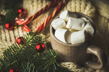 Cup of hot chocolate with marshmallow in knitted wool christmas setting. Hot winter drinks in christmas environment. Cozy winter mood