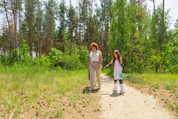 Fototapeta premium Grandmother and children walking with skateboards in the forest.