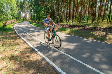 Fototapeta premium Young father with his little daughter on bicycle in summer sunny forest