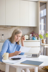 Senior woman looking worried and stressed, calculating expenses and reviewing financial documents...