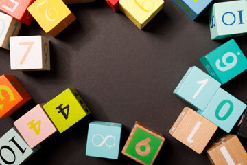 Brightly colored wooden blocks with numbers on a dark background. Concept of education, childhood,...