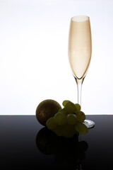 Empty Classic champagne glass next to bunch of grapes and Christmas ball