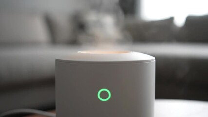 Modern white essential oil diffuser releasing mist, glowing in a cozy home environment