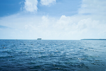 Open Ocean with Serene Horizon and Distant Small Island Under Blue Sky
