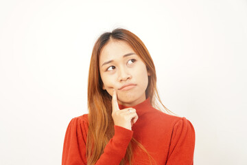 Close-up of a pensive young woman thinking deeply with her index finger on her chin, looking up for inspiration or a solution.