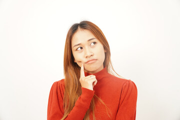 Close-up of a pensive young woman thinking deeply with her index finger on her chin, looking up for inspiration or a solution.