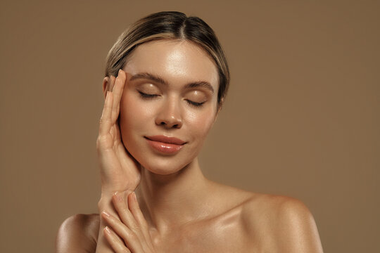 Natural beauty portrait of young woman with healthy glowing skin on beige background