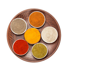 Spices: turmeric, paprika, cardamom, nutmeg, black pepper and allspice on a large plate on a white background.