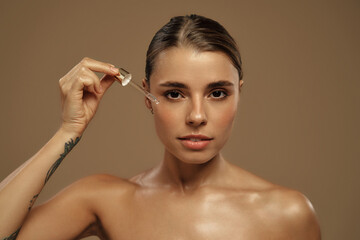 Naklejka premium Beautiful woman applying facial serum with glass dropper