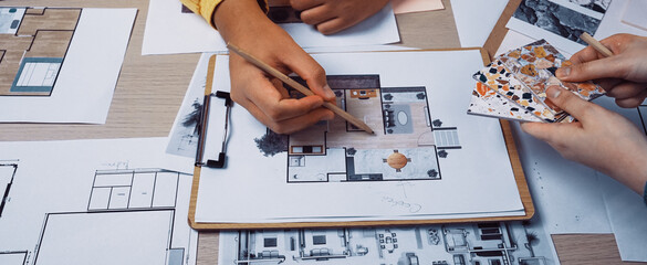 Close-up view of hands engaged in a collaborative design project showcasing sketches and color swatches, emphasizing creativity and teamwork in a bright, organized workspace. SACTR