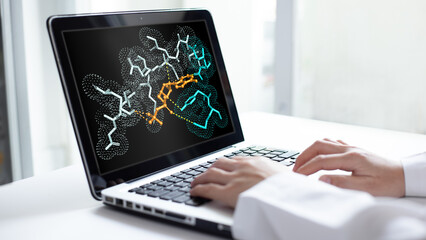 A scientist analyzes molecular simulation results and protein drug interactions on a laptop screen to develop new pharmaceutical drugs in a laboratory.