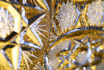 Golden crystal glass macro with detailed geometric cuts, bright reflections and shimmering bokeh. Abstract luxury background suitable for festive themes.