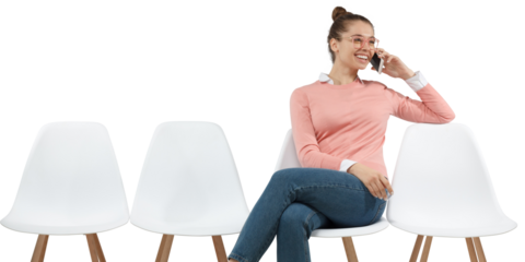 Smiling young woman sitting on chair talking on smartphone having pleasant phone conversation casually