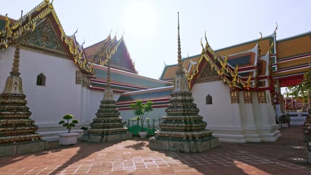 Video view of ornate stupas and Wat Pho temple in Bangkok, Thailand, highlighting richly decorated towers covered with colorful ceramic floral patterns in bright daylight.