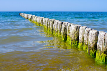 Weathered sea wall breakwaters in calm ocean water