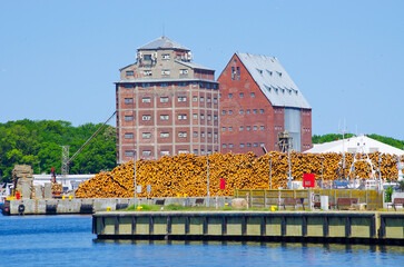 Large industrial building with log pile by waterfront dock, Swinoujscie, Poland